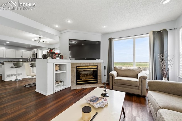 245 Turf Trail Pl, Fountain, CO 80817 - living room featuring dark wood-type flooring, a textured ceiling, recessed lighting, and a tile fireplace