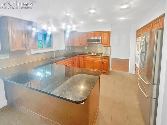 570 Ore Cart Way, Monument, CO 80132 - kitchen with stainless steel appliances, dark stone counters, a peninsula, light tile patterned flooring, and brown cabinetry