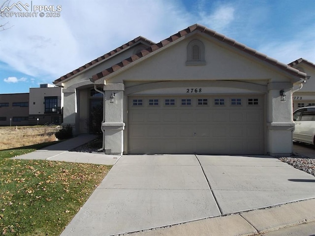 2768 Thrush Grv, Colorado Springs, CO 80920 - view of front of home featuring a garage, stucco siding, driveway, and a tile roof