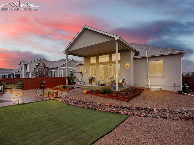 12646 Windingwalk Dr, Peyton, CO 80831 - back of house at dusk with a patio, stucco siding, and a shingled roof