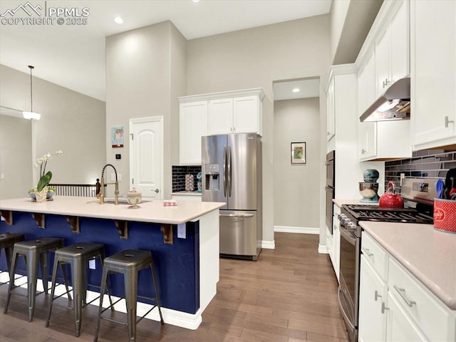 12646 Windingwalk Dr, Peyton, CO 80831 - kitchen featuring appliances with stainless steel finishes, under cabinet range hood, white cabinetry, tasteful backsplash, and recessed lighting