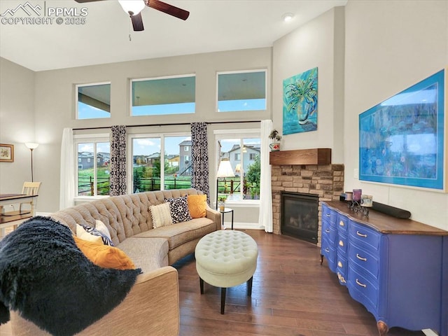 12646 Windingwalk Dr, Peyton, CO 80831 - living area featuring dark wood-style flooring, plenty of natural light, ceiling fan, a stone fireplace, and a towering ceiling