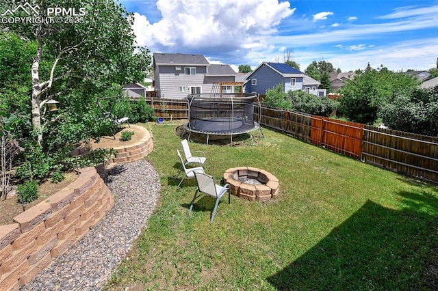 6290 Cording Ct, Colorado Springs, CO 80922 - fenced backyard featuring a trampoline, a fire pit, and a residential view