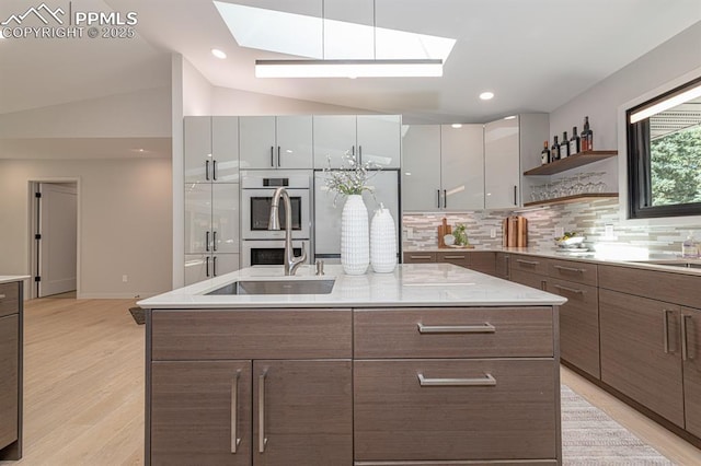 2510 Old Broadmoor Rd, Colorado Springs, CO 80906 - kitchen with a skylight, modern cabinets, decorative backsplash, an island with sink, and lofted ceiling