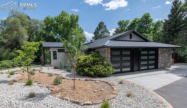2510 Old Broadmoor Rd, Colorado Springs, CO 80906 - modern home featuring a standing seam roof, concrete driveway, a metal roof, a garage, and stone siding