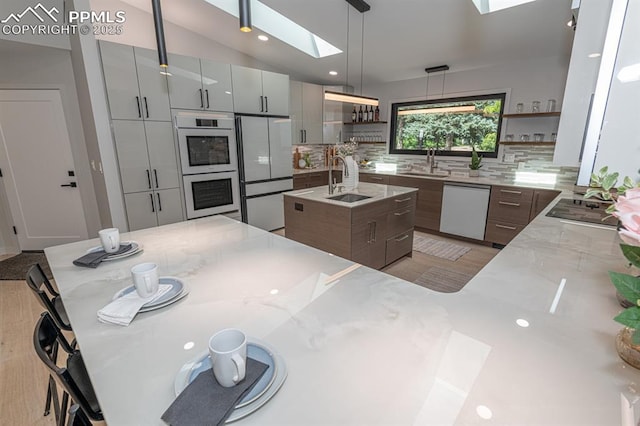 2510 Old Broadmoor Rd, Colorado Springs, CO 80906 - kitchen with white appliances, open shelves, a skylight, tasteful backsplash, and light stone counters