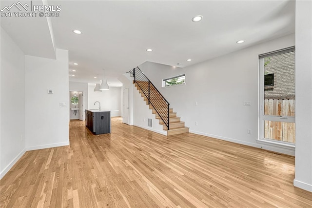 1231 Newton St, Denver, CO 80204 - unfurnished living room with stairway, light wood finished floors, and recessed lighting