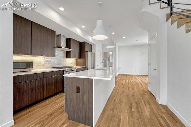 1231 Newton St, Denver, CO 80204 - kitchen with wall chimney range hood, appliances with stainless steel finishes, light wood finished floors, light countertops, and recessed lighting