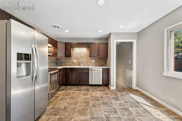1443 Luna Dr, Fountain, CO 80817 - kitchen featuring stainless steel appliances, light countertops, tasteful backsplash, dark brown cabinets, and light stone finish floors