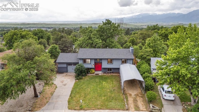 7030 Metropolitan St, Colorado Springs, CO 80911 - view of front of house with driveway, a front lawn, a mountain view, a chimney, and an attached garage
