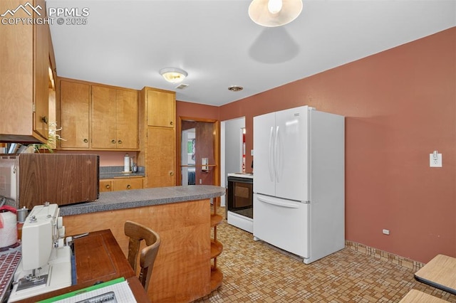 822 W Monroe St, Colorado Springs, CO 80907 - kitchen featuring freestanding refrigerator, light flooring, a peninsula, brown cabinetry, and stove