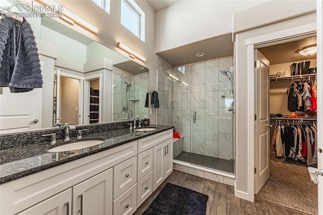 5960 Bennach Grv, Colorado Springs, CO 80927 - bathroom featuring double vanity, a walk in closet, a shower stall, and wood finished floors