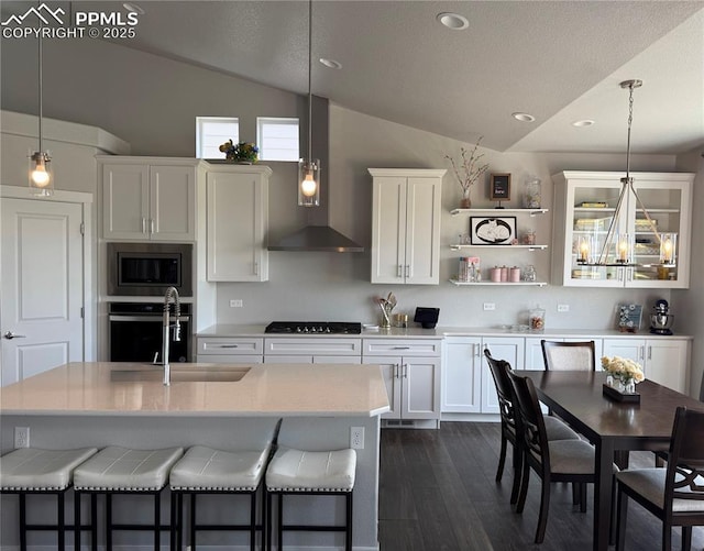 5960 Bennach Grv, Colorado Springs, CO 80927 - kitchen featuring lofted ceiling, appliances with stainless steel finishes, wall chimney range hood, light countertops, and white cabinets