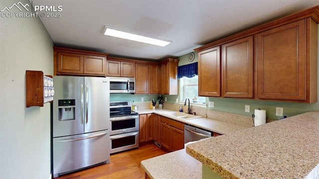 2160 Ance St, Strasburg, CO 80136 - kitchen with stainless steel appliances, light wood-type flooring, a peninsula, and light countertops
