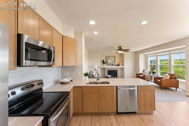 9891 Red Sage Dr, Colorado Springs, CO 80920 - kitchen featuring stainless steel appliances, open floor plan, a peninsula, a tiled fireplace, and ceiling fan