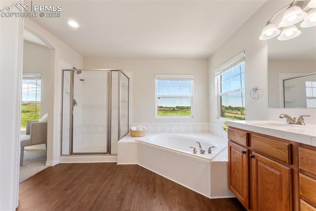 9891 Red Sage Dr, Colorado Springs, CO 80920 - full bathroom with vanity, a bath, a stall shower, and wood finished floors