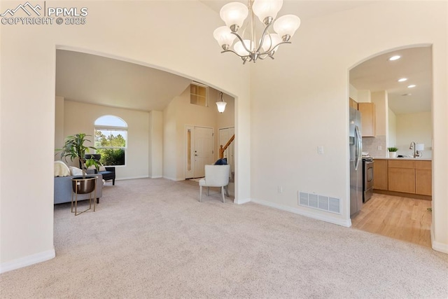 9891 Red Sage Dr, Colorado Springs, CO 80920 - living area featuring light carpet, arched walkways, a chandelier, stairs, and recessed lighting