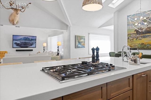 18 2nd St, Colorado Springs, CO 80906 - kitchen with stainless steel gas cooktop, light countertops, open floor plan, brown cabinetry, and high vaulted ceiling