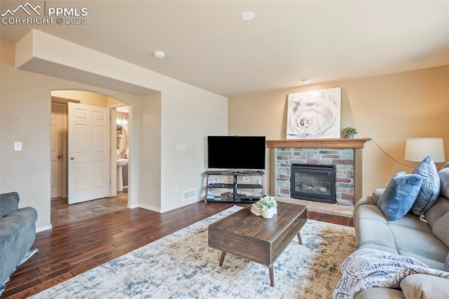 6372 Shooting Iron Way, Colorado Springs, CO 80923 - living room with wood finished floors, arched walkways, and a stone fireplace