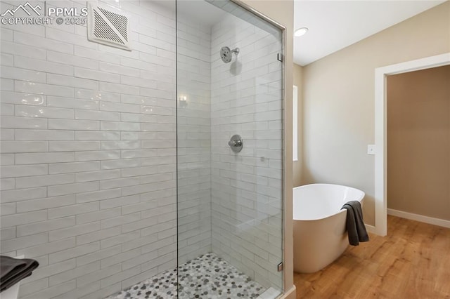 1320 Spring Valley Dr, Colorado Springs, CO 80921 - full bath featuring a stall shower, wood finished floors, and a freestanding tub