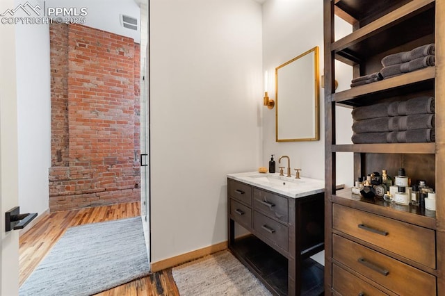 423 W 4th St, Pueblo, CO 81003 - bathroom with vanity, wood finished floors, and brick wall