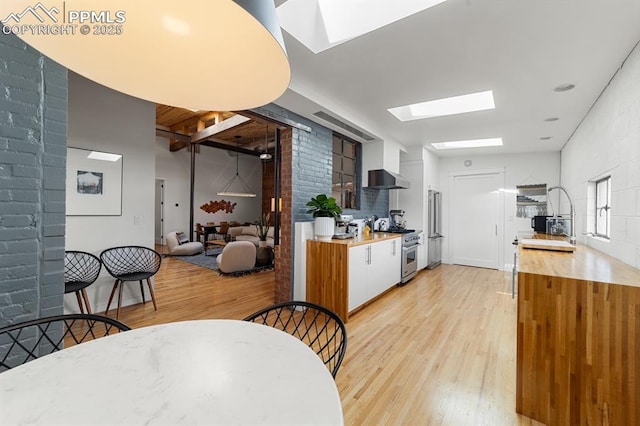 423 W 4th St, Pueblo, CO 81003 - kitchen featuring high quality appliances, a skylight, light wood-style floors, light countertops, and wall chimney exhaust hood