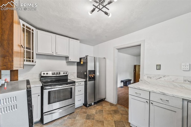 802 Alexander Rd, Colorado Springs, CO 80909 - kitchen with stainless steel appliances, glass insert cabinets, a textured ceiling, white cabinetry, and light stone counters