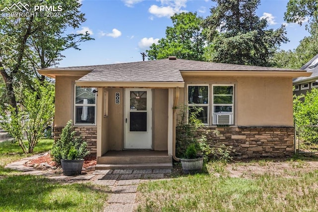 802 Alexander Rd, Colorado Springs, CO 80909 - view of exterior entry with stone siding, stucco siding, roof with shingles, and cooling unit