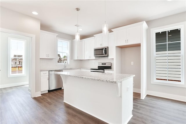 100 Hunters Way, Opelika, AL 36801 - kitchen with appliances with stainless steel finishes, white cabinetry, wood finished floors, a center island, and decorative backsplash