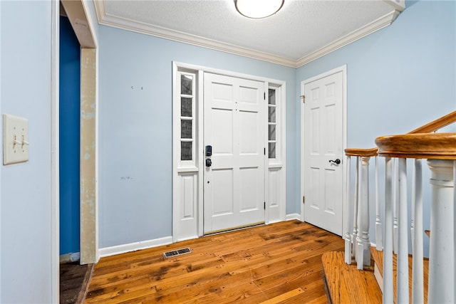 foyer entrance with a textured ceiling, ornamental molding, and hardwood / wood-style flooring