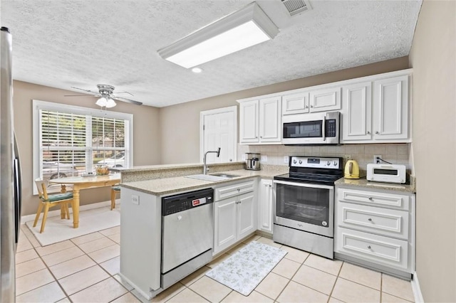 2260 Core Dr, Auburn, AL 36830 - kitchen featuring stainless steel appliances, a peninsula, white cabinetry, light tile patterned floors, and a textured ceiling