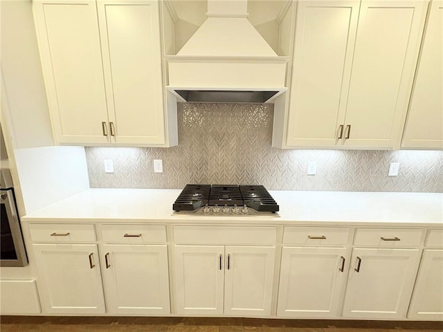 kitchen featuring custom exhaust hood, oven, gas stovetop, and backsplash