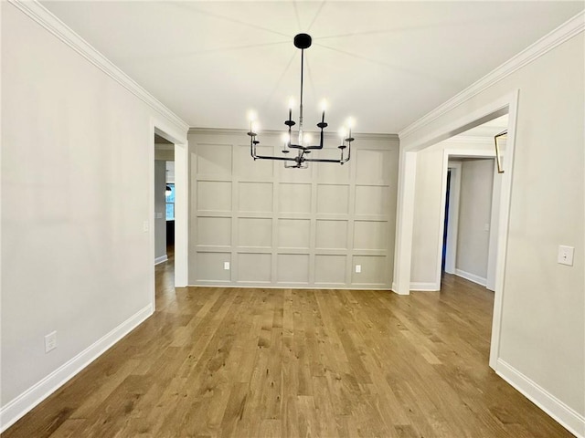 unfurnished dining area with crown molding, light hardwood / wood-style floors, and a chandelier