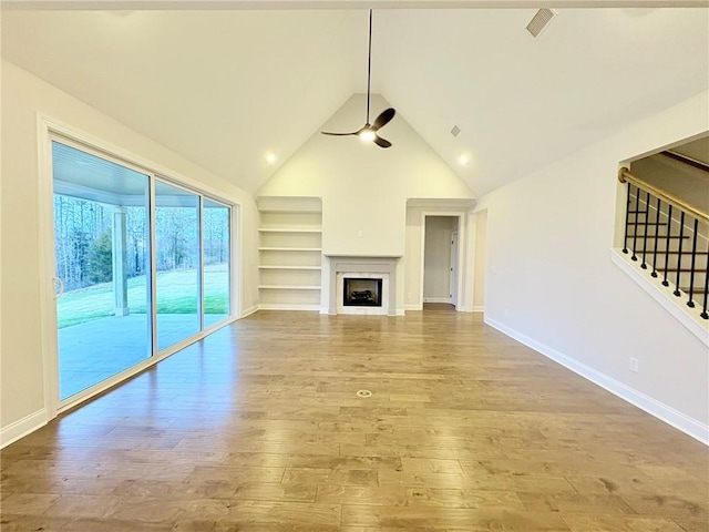 unfurnished living room featuring ceiling fan, vaulted ceiling, built in features, and light wood-type flooring