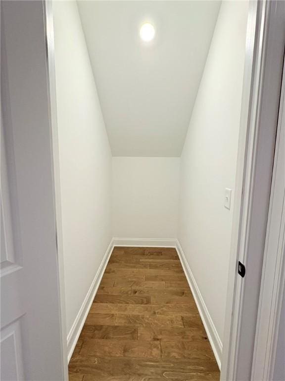 interior space featuring dark wood-style floors, lofted ceiling, and baseboards