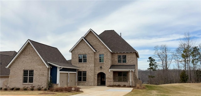 view of front facade with a front yard, concrete driveway, brick siding, and an attached garage