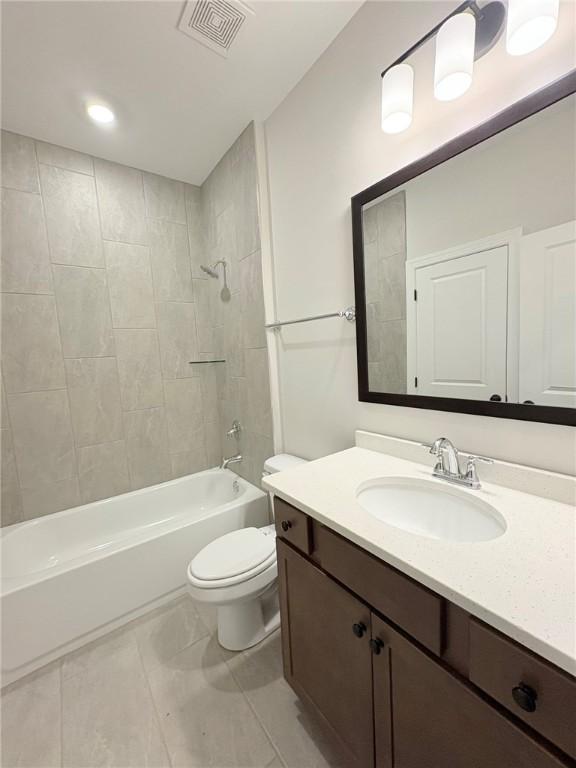 full bathroom with tiled shower / bath, vanity, and toilet