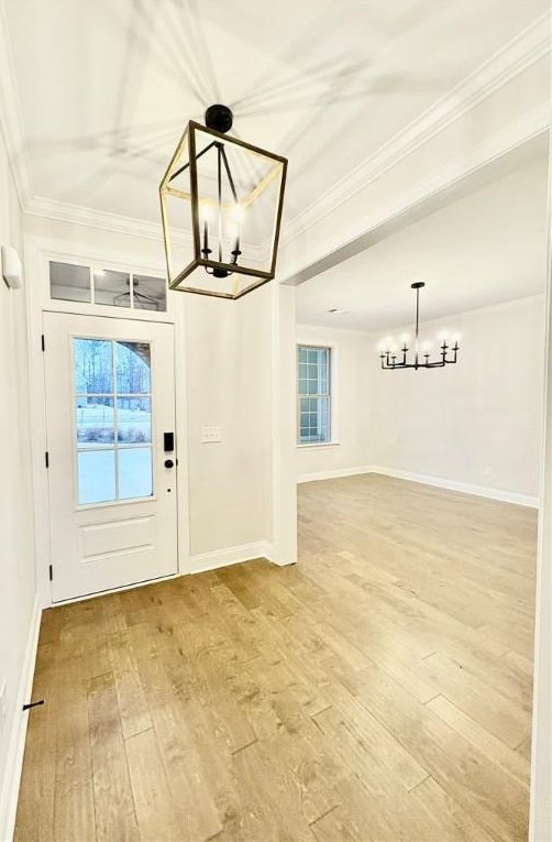 foyer with crown molding, hardwood / wood-style floors, and a notable chandelier