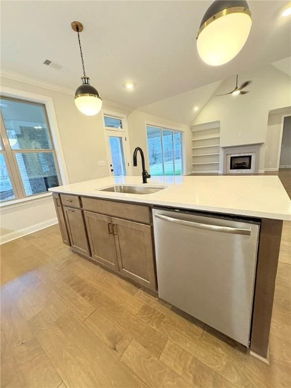 kitchen with a sink, open floor plan, light countertops, stainless steel dishwasher, and an island with sink