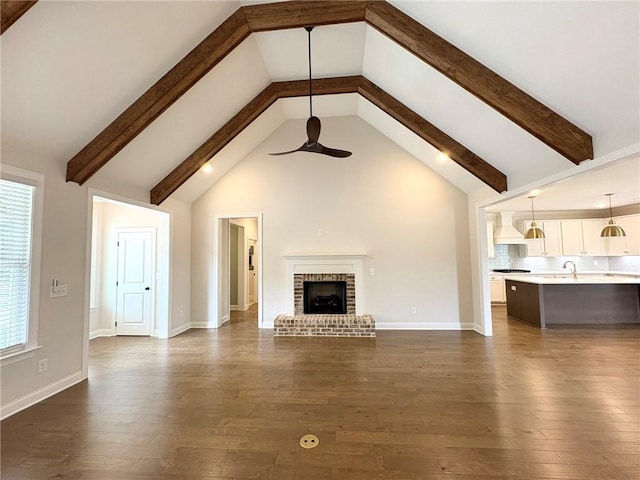 1649 James Burt Pkwy, Auburn, AL 36830 - unfurnished living room with a ceiling fan, beam ceiling, a sink, dark wood-type flooring, and a brick fireplace
