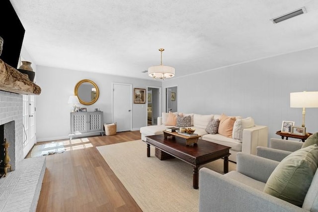 1324 Azalea Dr, Auburn, AL 36830 - living area featuring wood finished floors, a chandelier, a brick fireplace, and baseboards