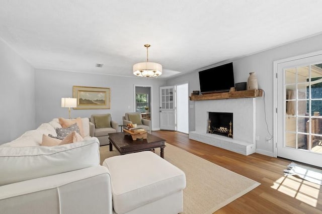 1324 Azalea Dr, Auburn, AL 36830 - living room with wood finished floors, a brick fireplace, a chandelier, and baseboards