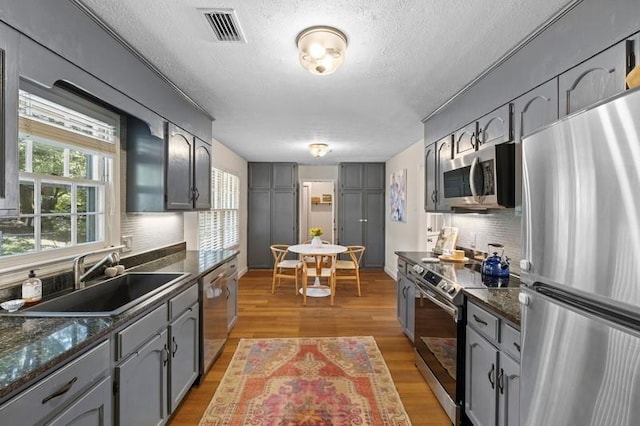 1324 Azalea Dr, Auburn, AL 36830 - kitchen featuring appliances with stainless steel finishes, a sink, decorative backsplash, gray cabinetry, and light wood-type flooring