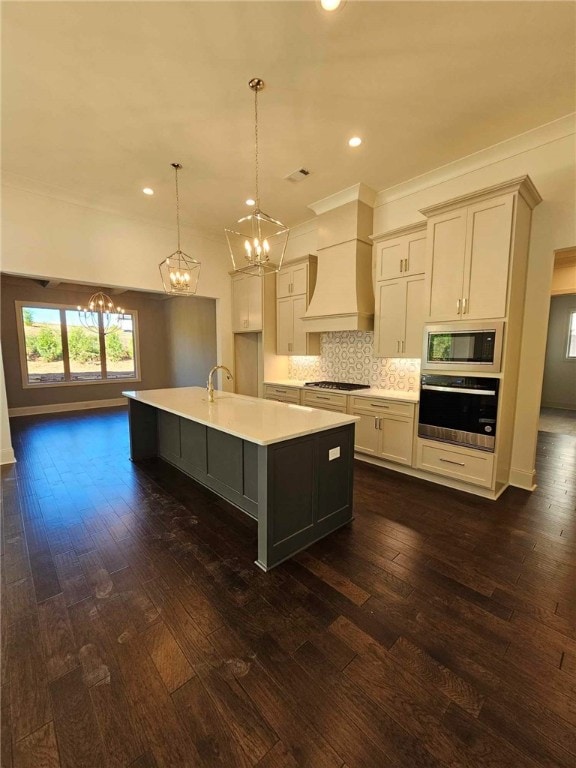 kitchen with custom exhaust hood, a center island with sink, decorative light fixtures, dark hardwood / wood-style flooring, and stainless steel appliances