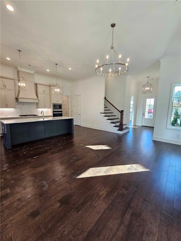 interior space with a large island with sink, decorative light fixtures, and custom exhaust hood