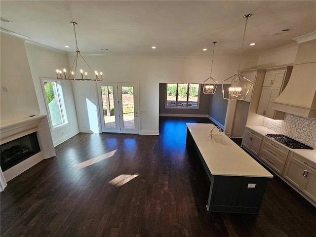 kitchen with decorative light fixtures, backsplash, a center island with sink, and stainless steel gas cooktop