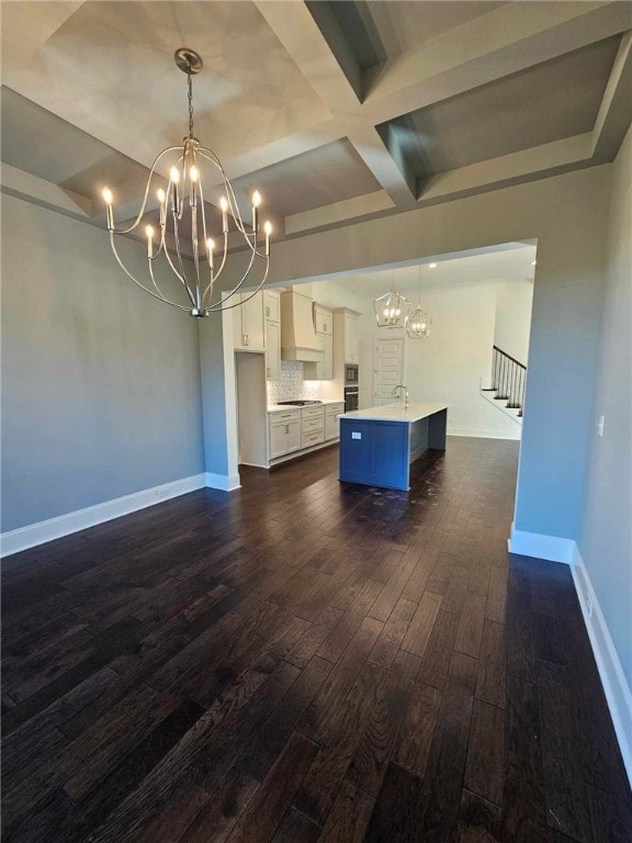 kitchen featuring beam ceiling, white cabinetry, a kitchen island with sink, and decorative light fixtures