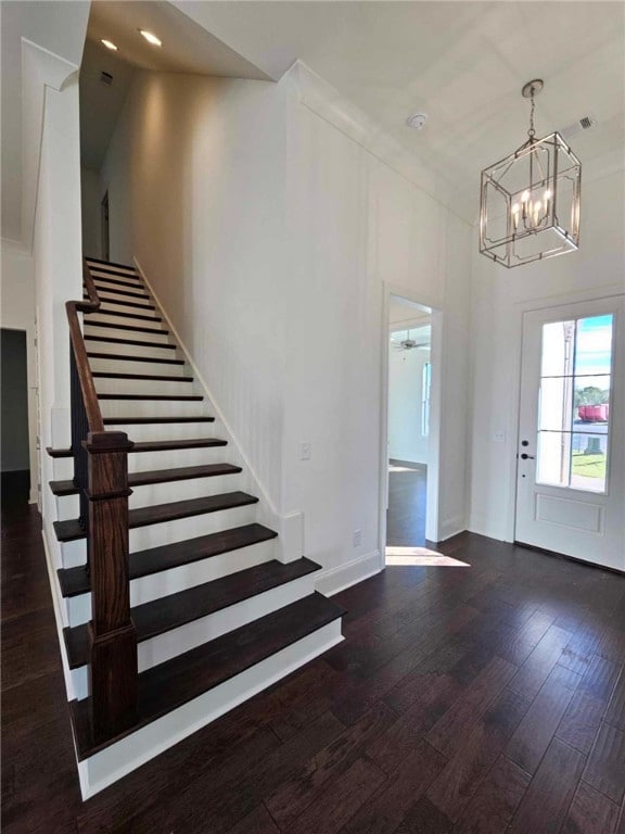 entryway with dark wood-type flooring and ceiling fan with notable chandelier