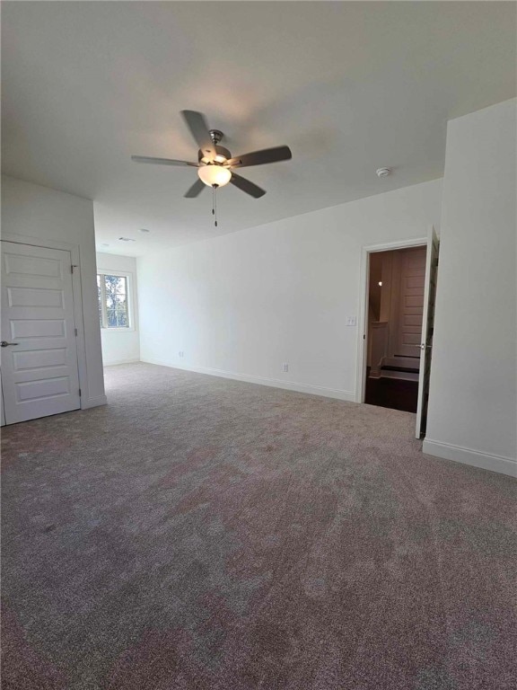 spare room featuring ceiling fan and dark colored carpet