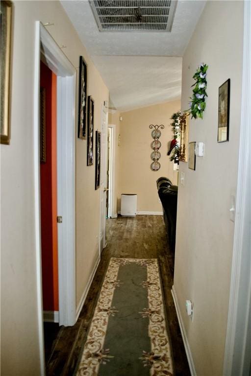 hall featuring baseboards, visible vents, and dark wood-type flooring